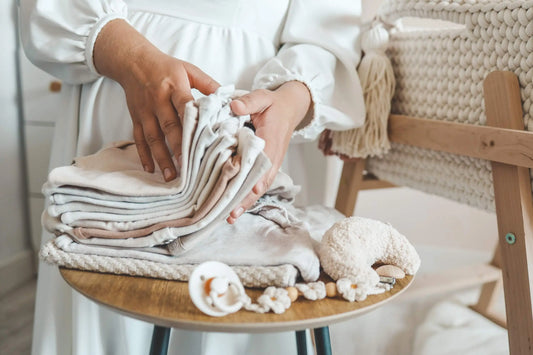 Pregnant woman organizing baby supplies and diapers while preparing the nursery for her newborn